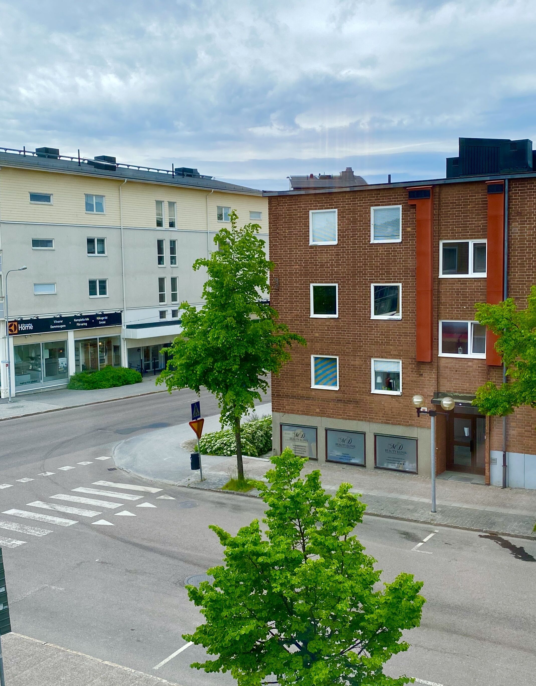 En byggnad med flera våningar, en fasad av tegel, en tydligt markerad entré och ett övergångsställe för fotgängare.