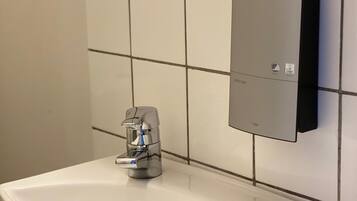 Une salle de bain avec un lavabo blanc, un robinet moderne et un distributeur de savon fixé au mur.