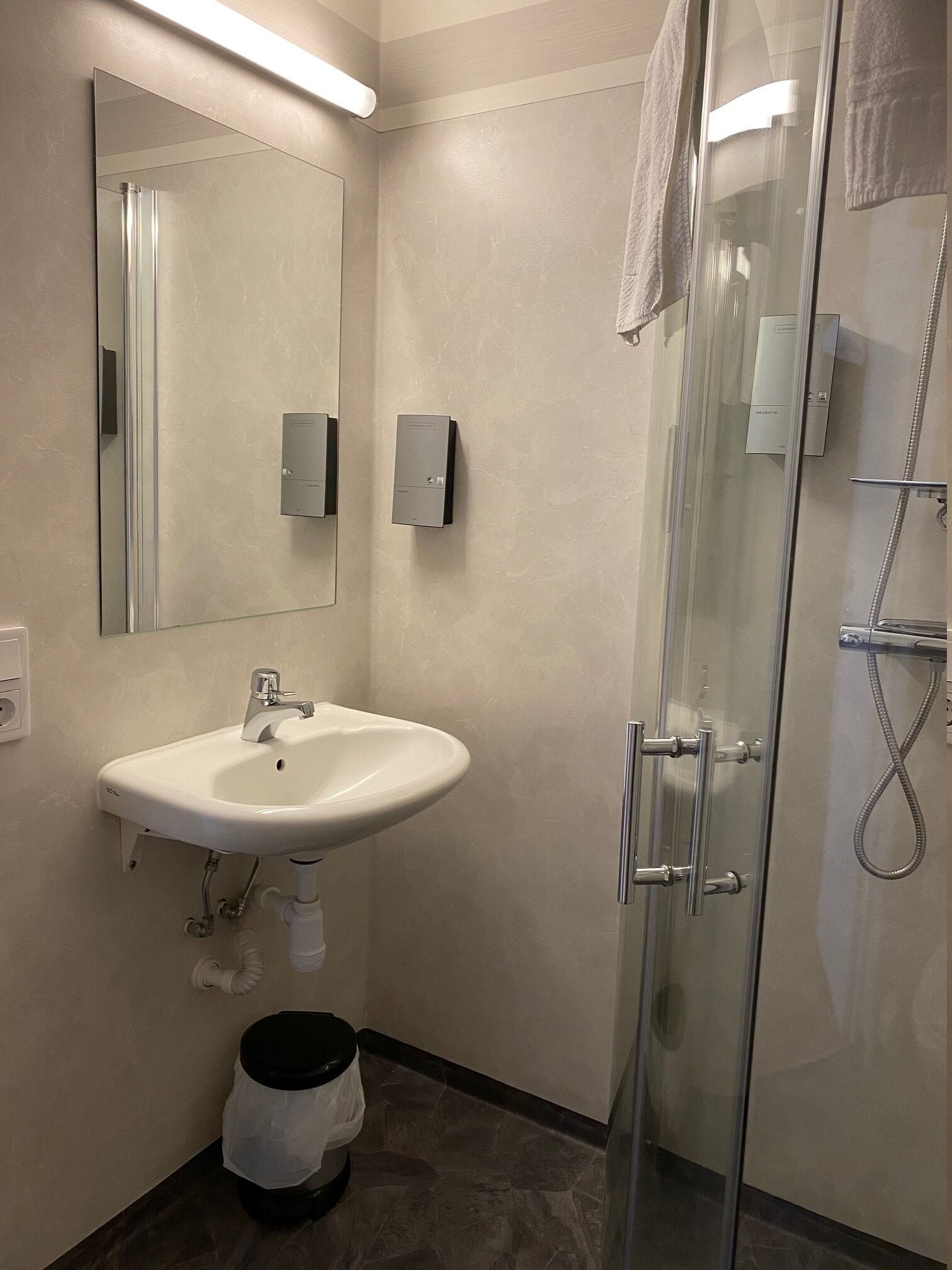 Une salle de bain moderne avec un lavabo blanc, une douche en verre et un miroir.