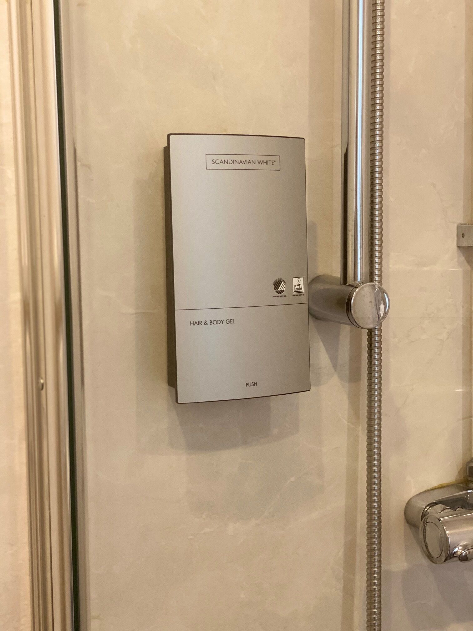 Un panneau de commande de douche moderne, de couleur « blanc scandinave », doté d’un bouton-poussoir et d’un bouton de réglage.