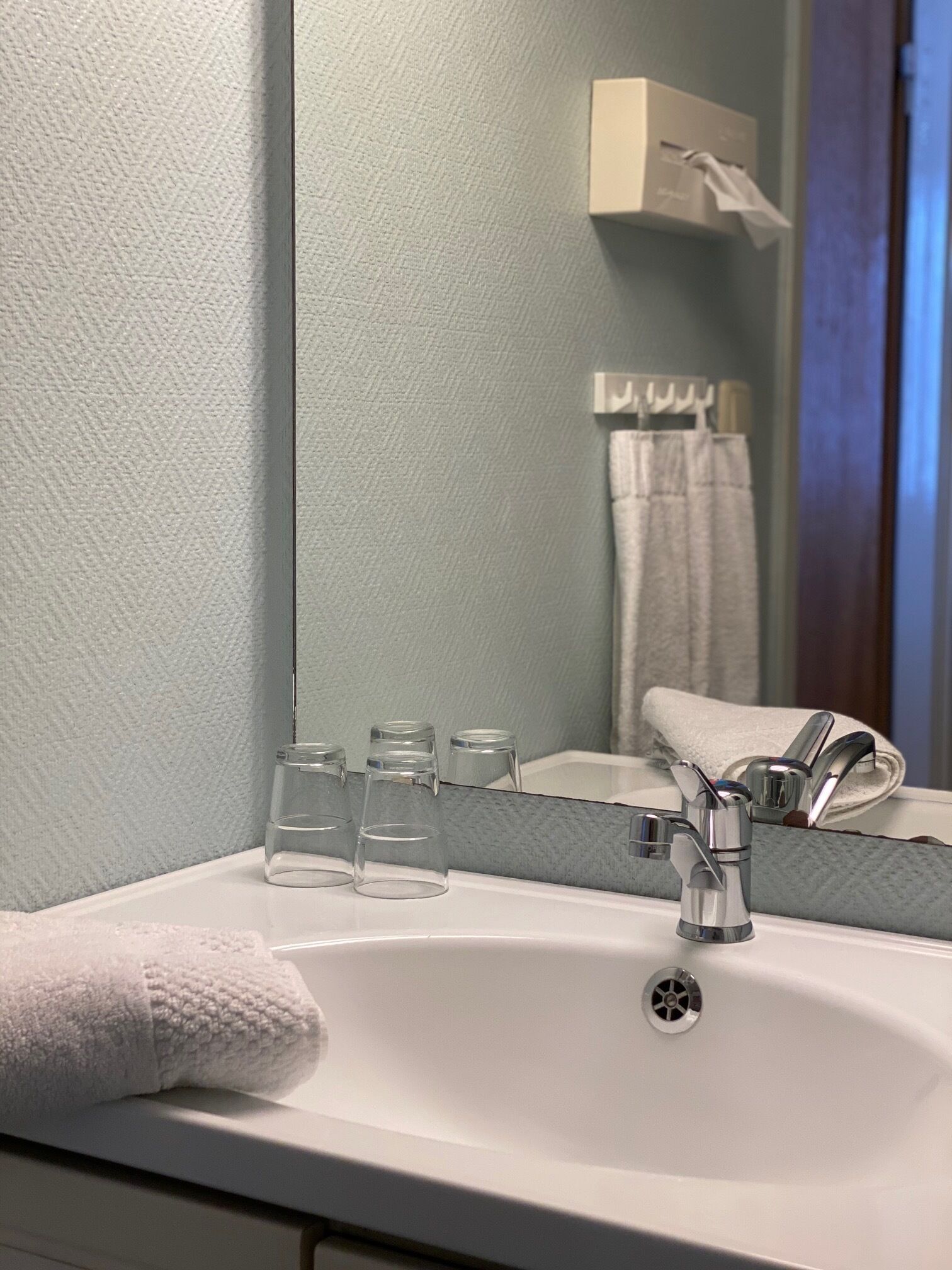 A bathroom with a white sink, a mirror, and a towel.