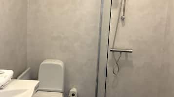 Een badkamer met toilet, douchecabine en wastafel.