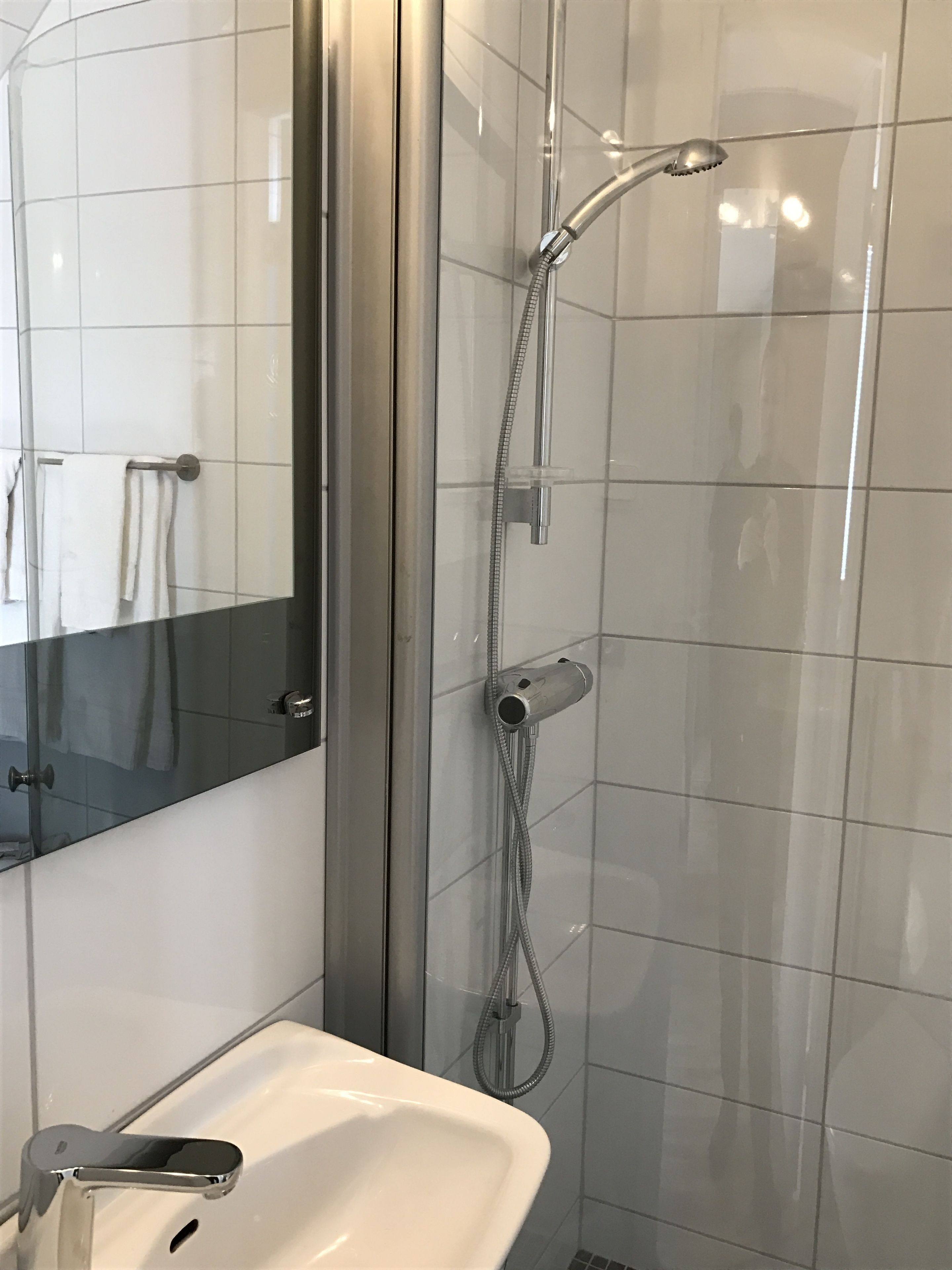 Une salle de bain moderne avec une douche à parois de verre, un lavabo blanc et un miroir.