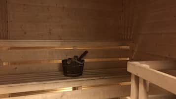 A sauna with wooden benches and a metal bucket.