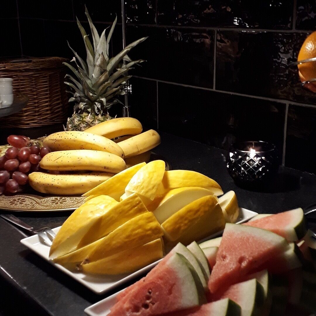 A fruit platter with bananas, grapes, pineapple, and watermelon slices on a plate.