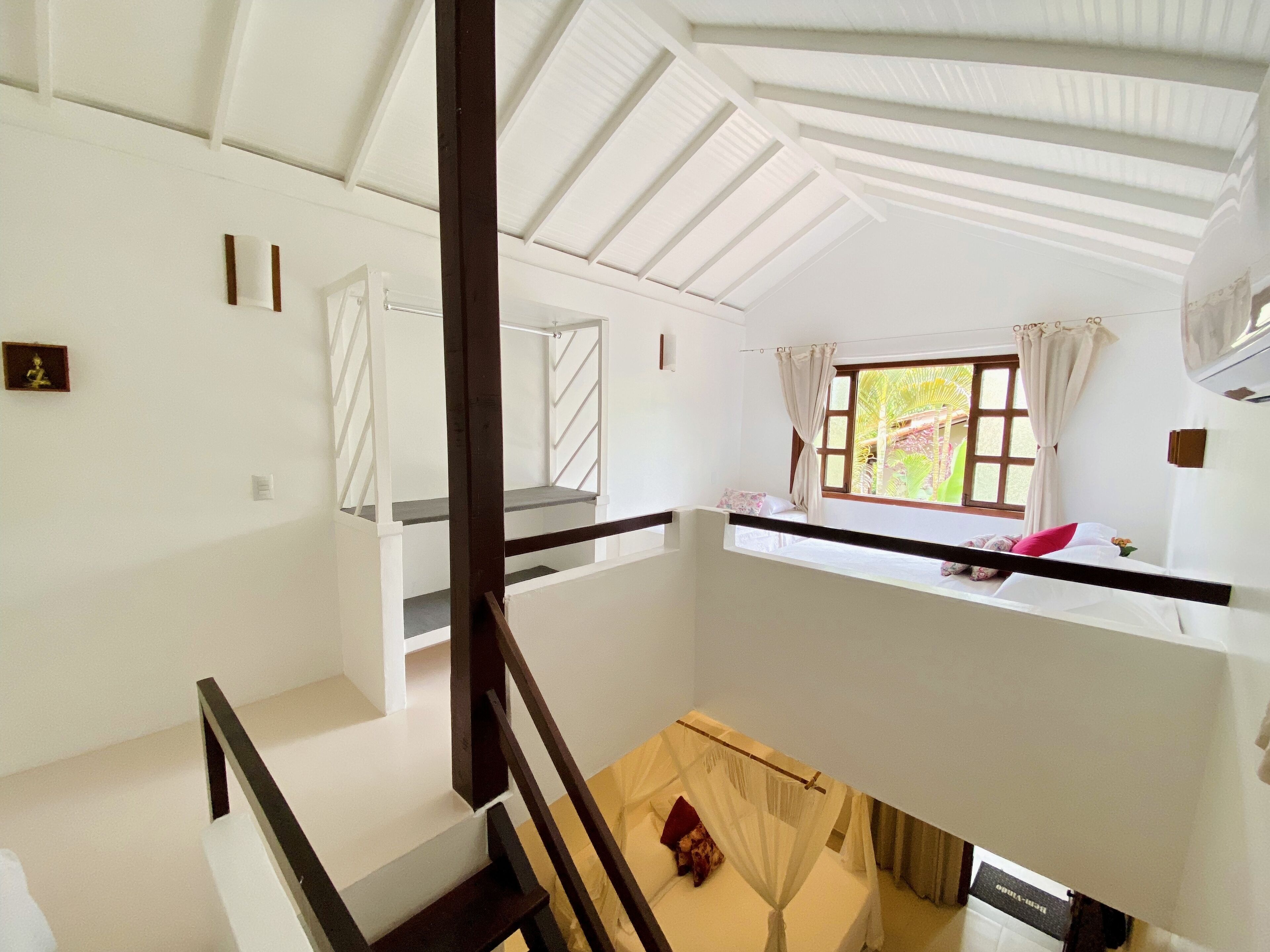 A room with a bunk bed, a window with curtains, a small table, and a bed with a canopy.