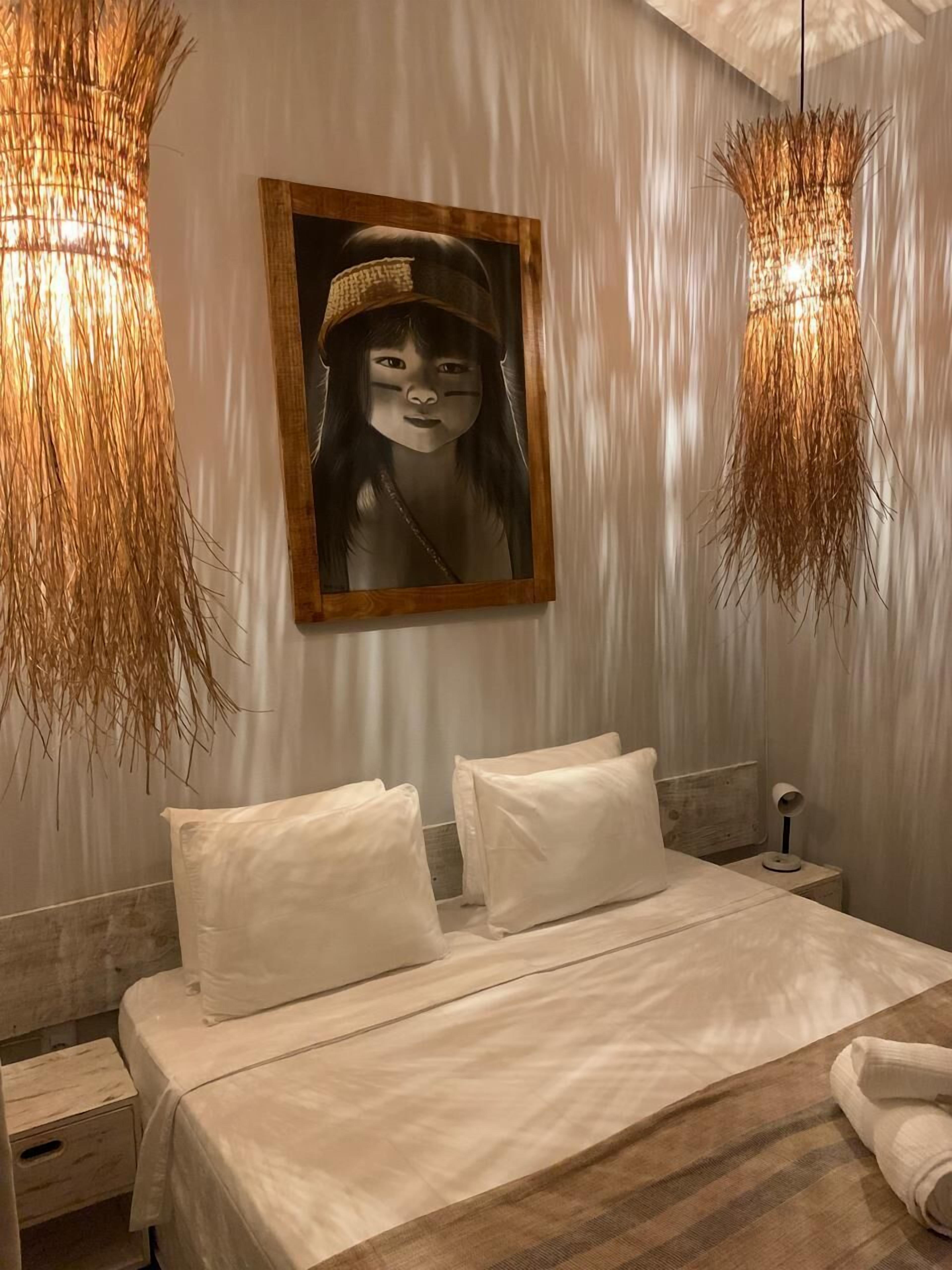 Ein Schlafzimmer mit einem Bett, zwei Kissen, einem Nachttisch, einer Lampe und einem Bild an der Wand.