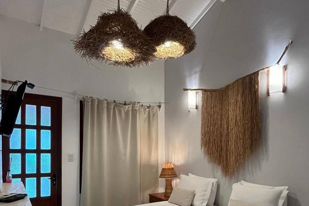 A bedroom with a bed, bedside lamp, and a hanging light fixture.