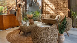 Ein modernes Interieur mit Rattanmöbeln, einer Steinwand und hängenden Pflanzen.