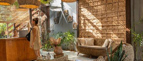 A modern interior with wicker furniture, a stone wall, and hanging plants.