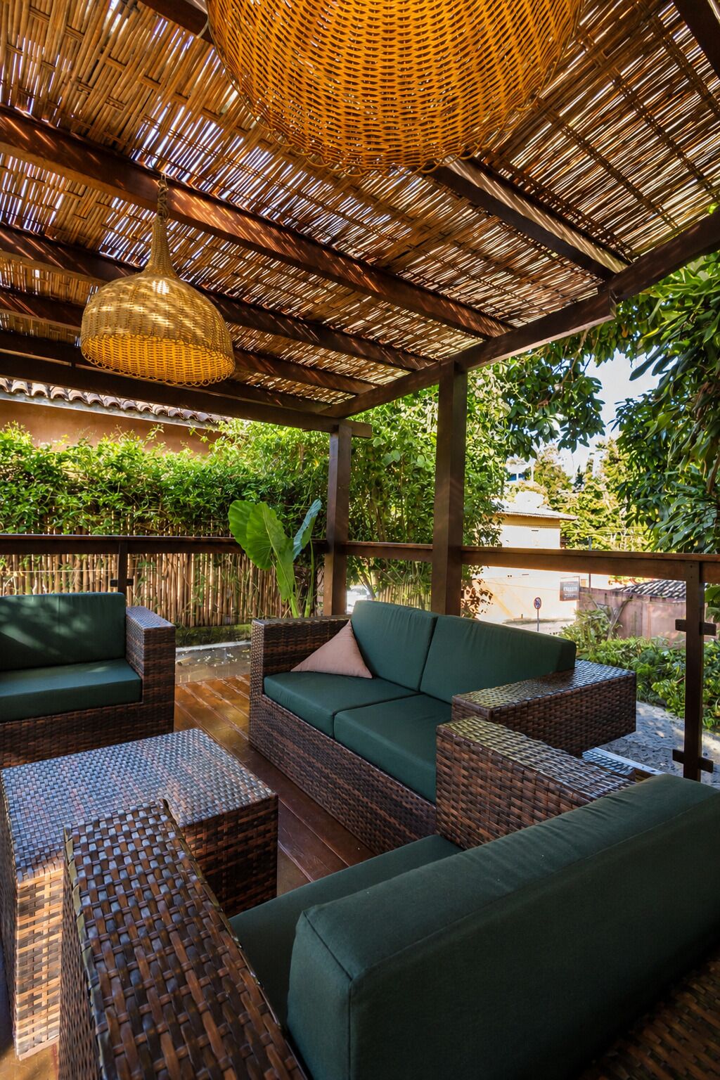 A covered outdoor seating area with wicker furniture and a woven ceiling.