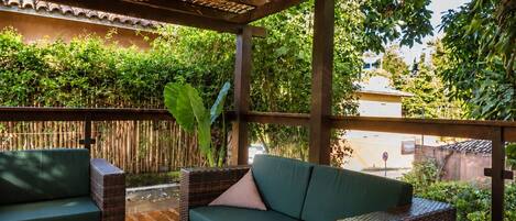 A covered outdoor seating area with wicker furniture and a woven ceiling.