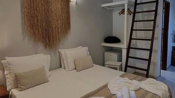 Quarto com cama, almofadas, um adorno pendurado, uma prateleira com um objeto preto e uma escada de madeira.