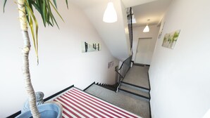 Una escalera con alfombra a rayas rojas y blancas, una palmera y una barandilla de metal.