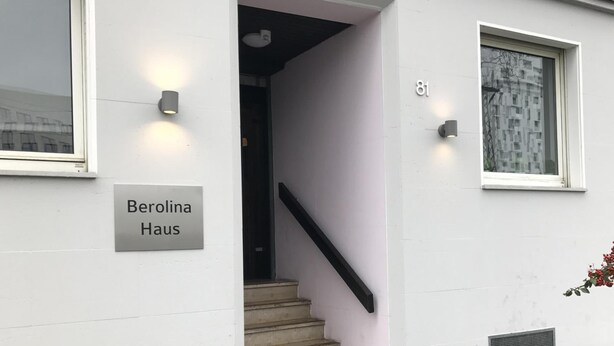 Fachada de un edificio con una escalera, un cartel que dice "Berolina Haus" y un ventanal con el número 81.