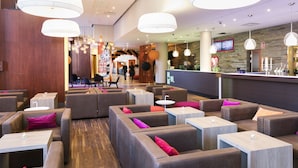 Un espace de détente moderne, avec des canapés, des tables et des lampes suspendues.