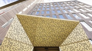 Un bâtiment moderne doté d’une structure métallique ajourée originale à l’entrée.