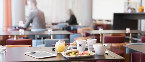 Desayuno preparado para dos personas, con una mesa puesta, un plato de comida, un vaso de zumo de naranja y dos tazas de café.