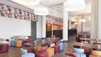 Um restaurante moderno com assentos coloridos, um bar e um mural na parede.