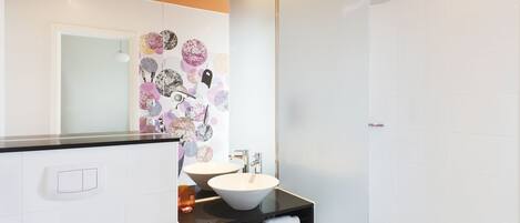 Une salle de bain moderne avec un comptoir noir, un lavabo blanc et un grand miroir.