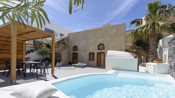 A pool area with a pergola, lounge chairs, and a dining set. - Casa Santantonio (Santorini)