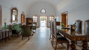 A spacious room with a high ceiling, a dining table with chairs, and a large mirror on the wall. - Casa Santantonio (Santorini)