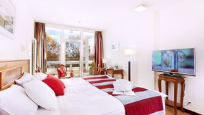 Habitación de hotel con dos camas, televisión y vistas al exterior.