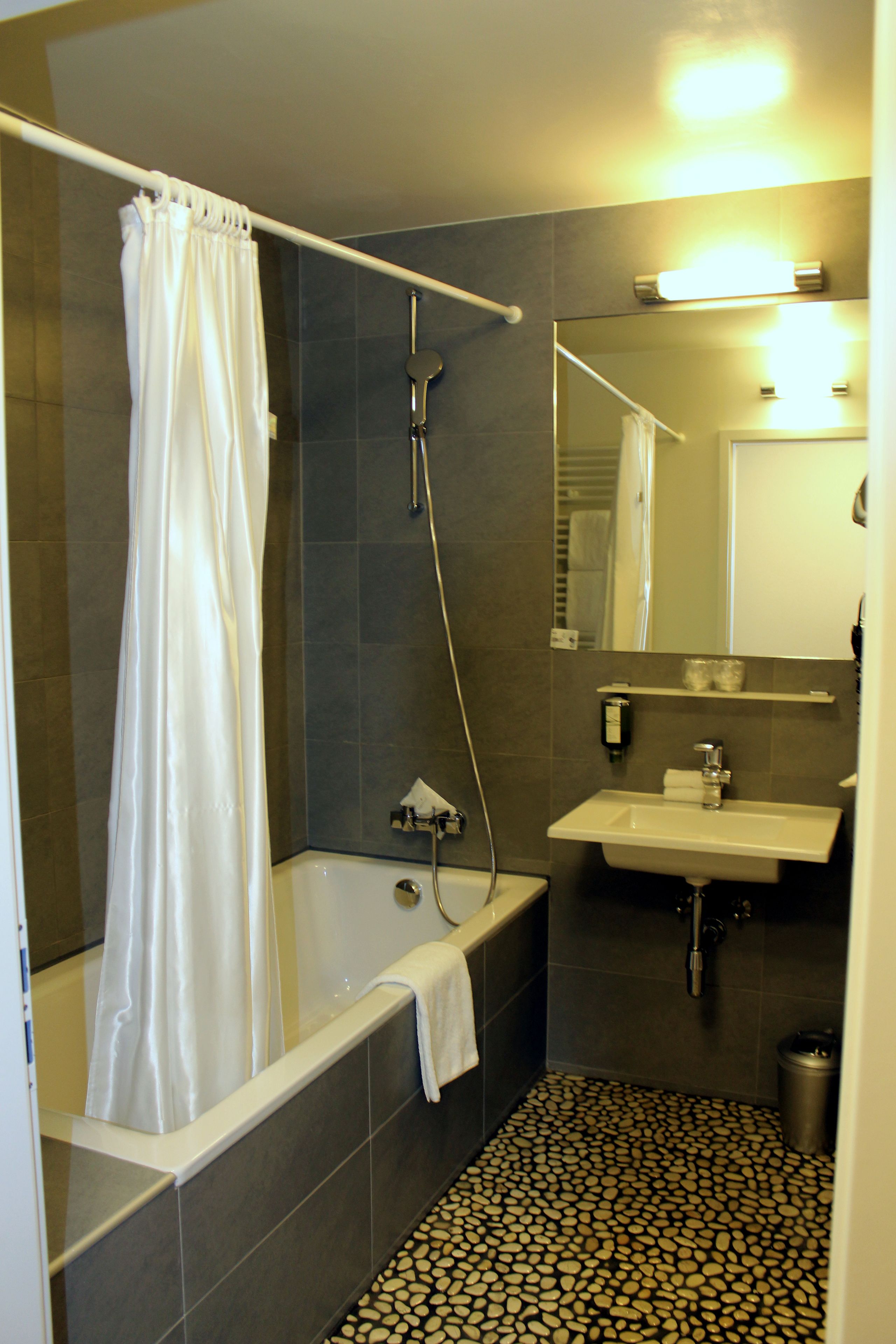 Une salle de bain avec une baignoire, une douche, un lavabo et un sol carrelé.