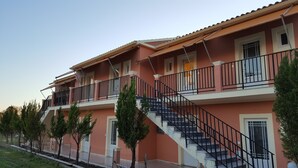 Un edificio de varios pisos con fachada roja, barandales negros y una escalera que conduce al nivel superior.