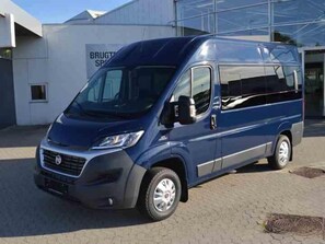 Un fourgon bleu est garé devant un immeuble sur lequel on peut lire l’inscription « BRUGTS ».