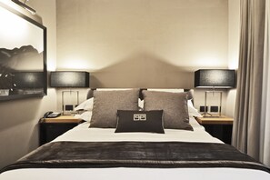 A hotel room with a neatly made bed, two bedside tables with lamps, a telephone, and a mirror on the wall. - Parioli Place (Rome)