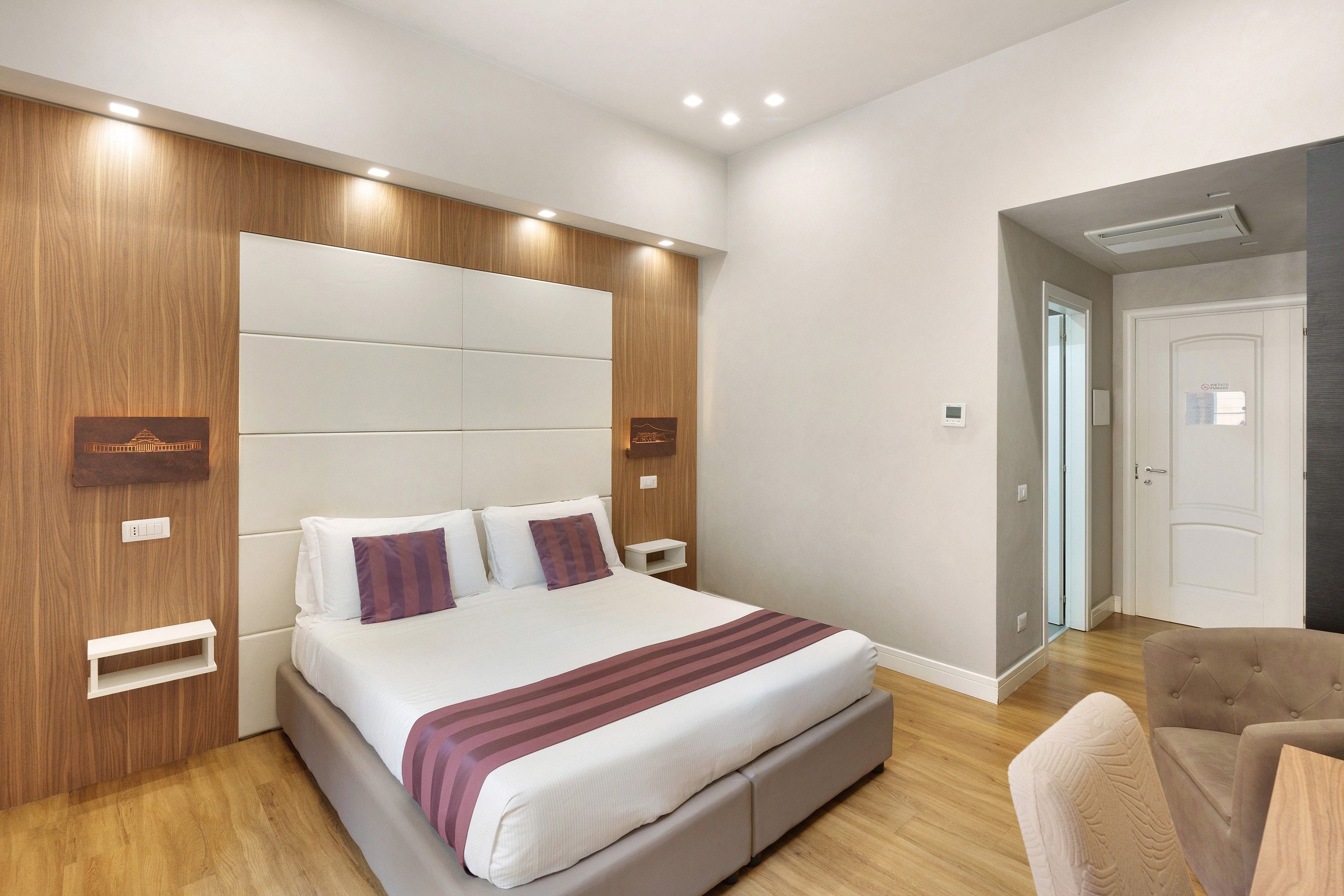 A modern hotel room with a large bed, built-in storage, and a seating area.