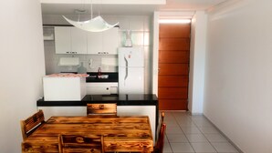 Eine moderne Küche mit weißen Schränken, einer schwarzen Arbeitsplatte und einem Holzes Esstisch mit Stühlen.