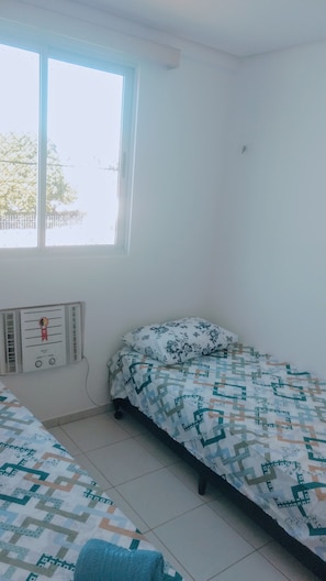 Quarto com duas camas, um radiador e uma janela.
