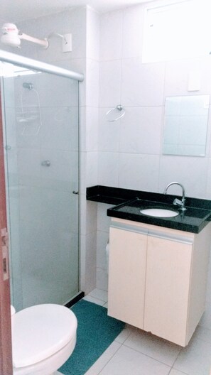 Een badkamer met toilet, wastafel, douche en een spiegel aan de muur.