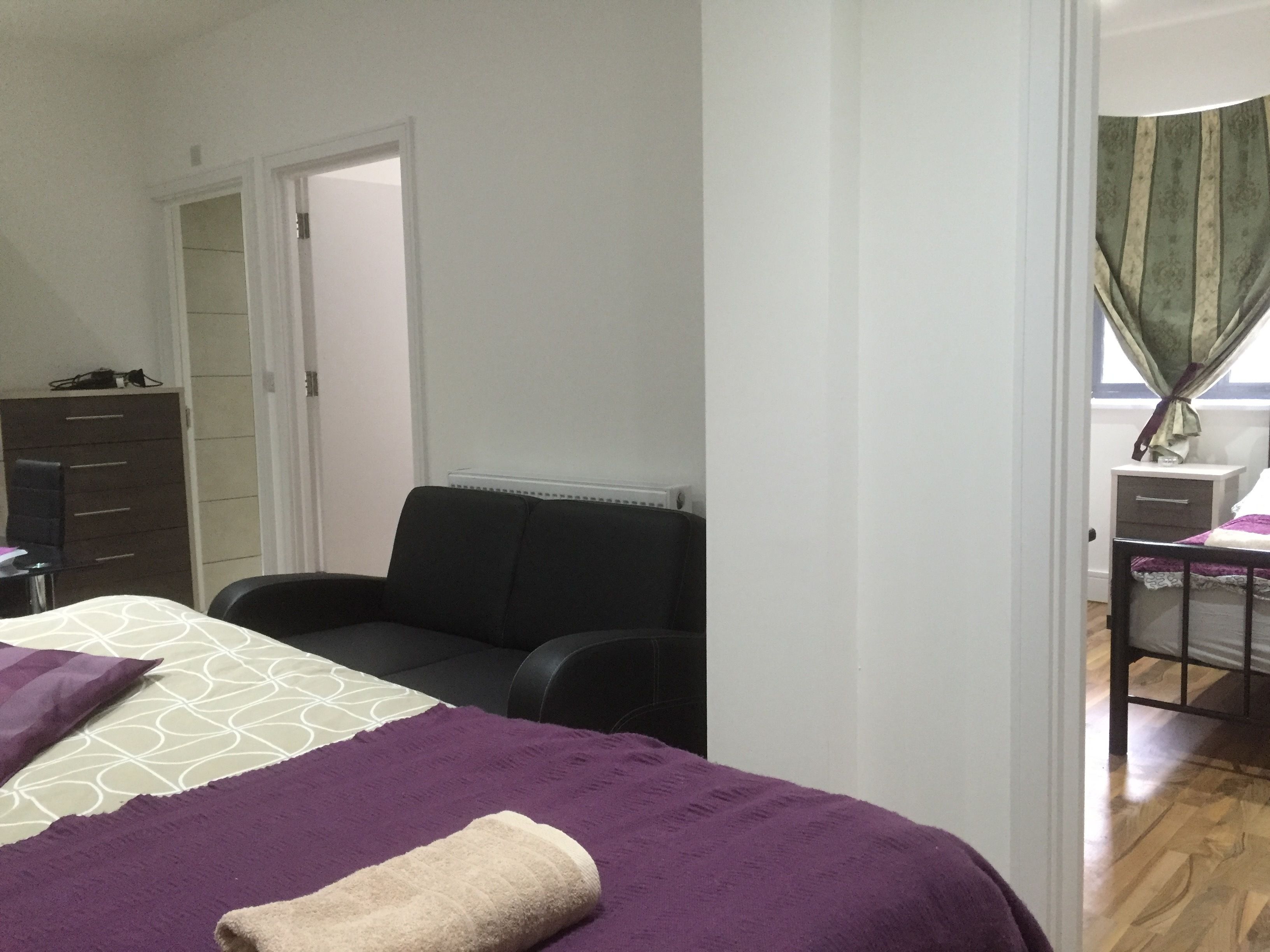 A bedroom with a bed, a chair, a desk, and a wardrobe.