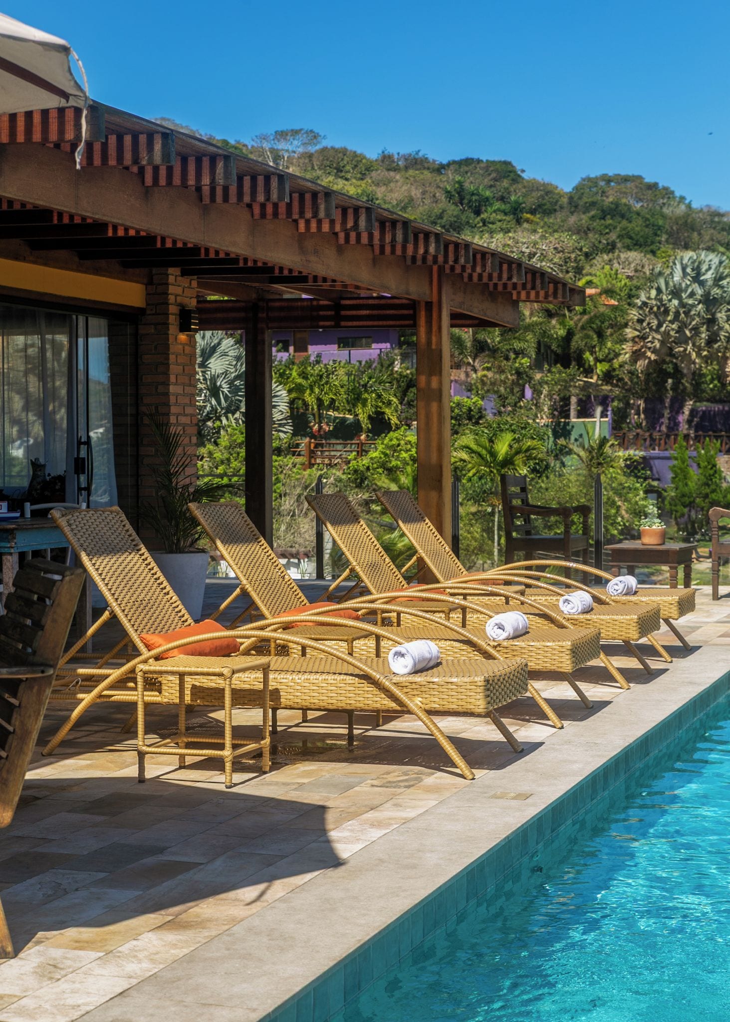 A poolside area with wicker lounge chairs and a covered seating area.