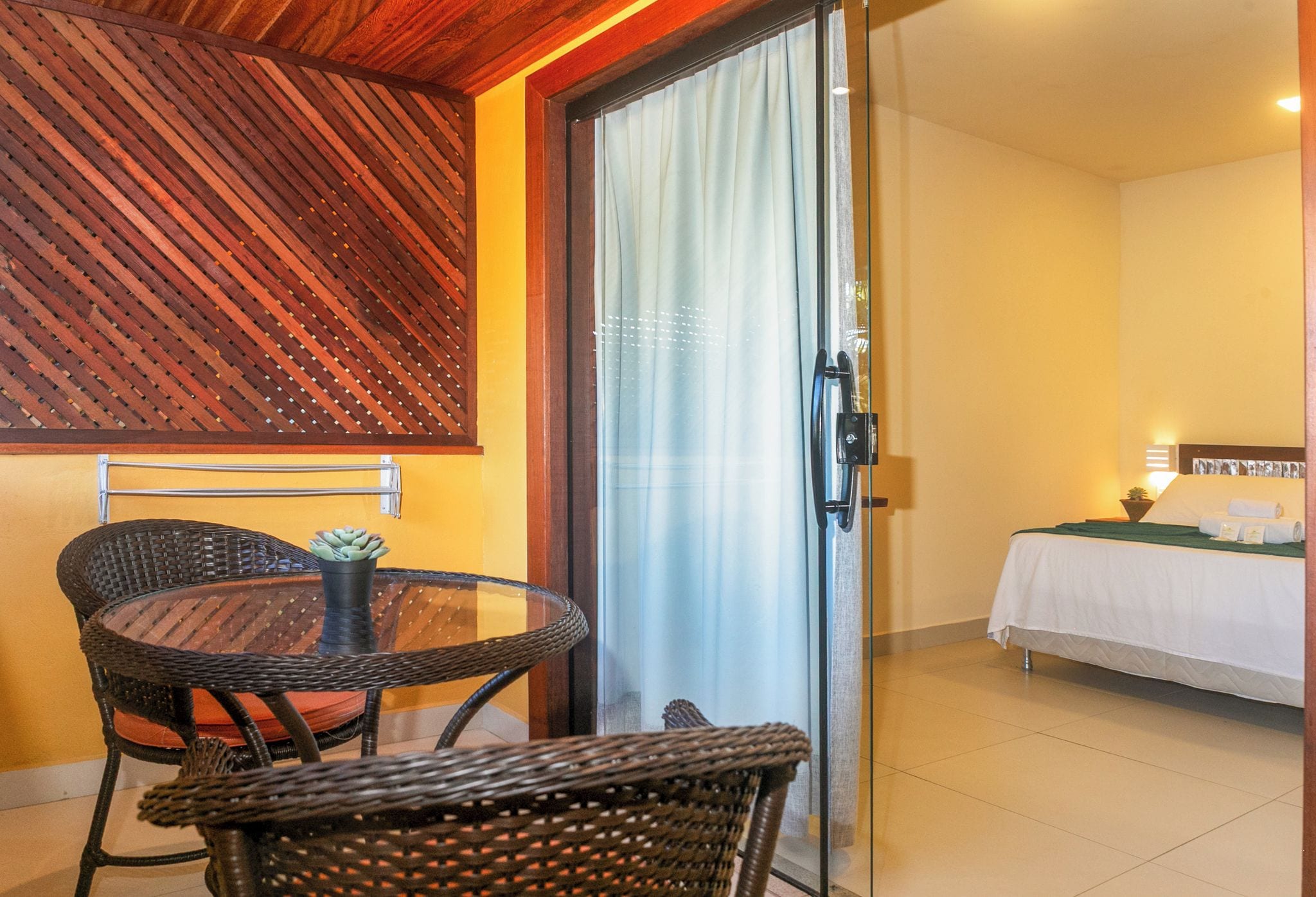A room with a bed, a table with chairs, and a sliding glass door leading to a balcony.