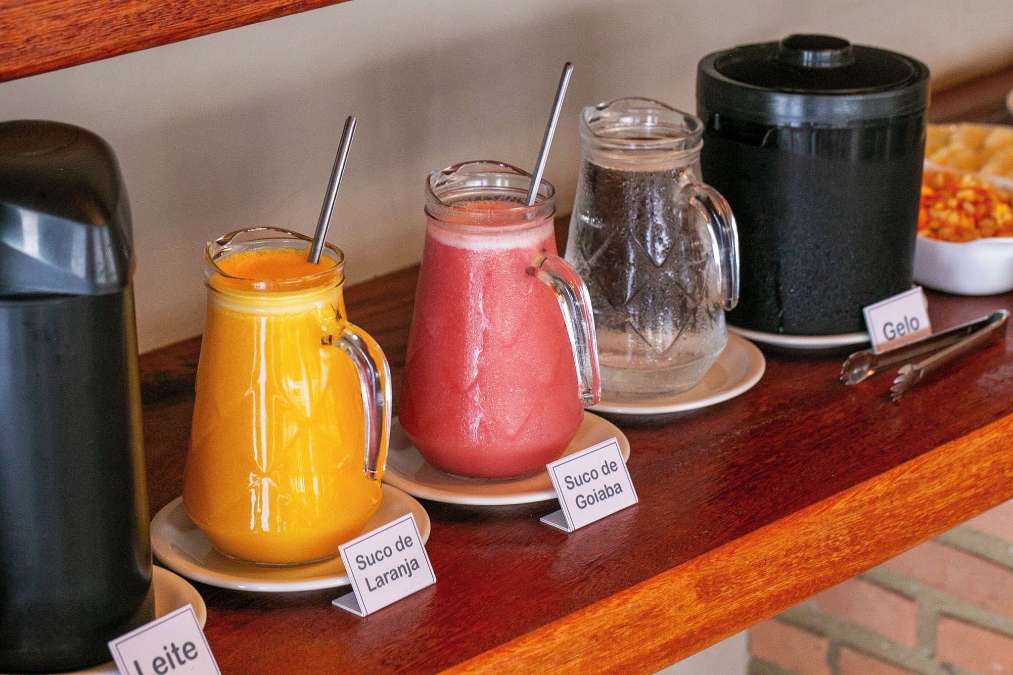 Mostrador de buffet con varios jugos de frutas y una cafetera.