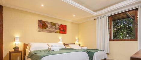 A hotel room with two beds, a painting on the wall, and a window with curtains.