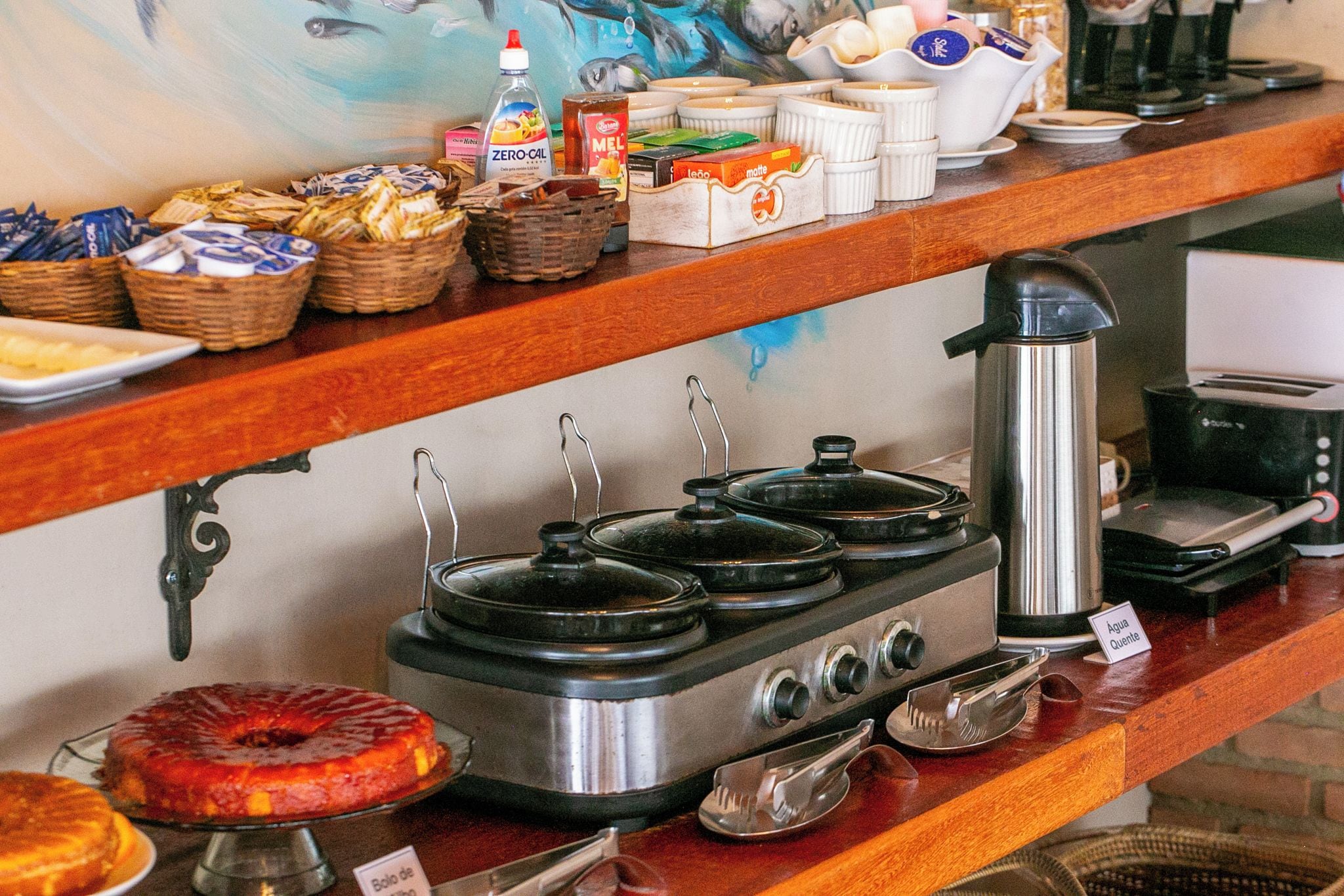 Montaje de bufé con diferentes alimentos, una máquina de café y una estufa con ollas.