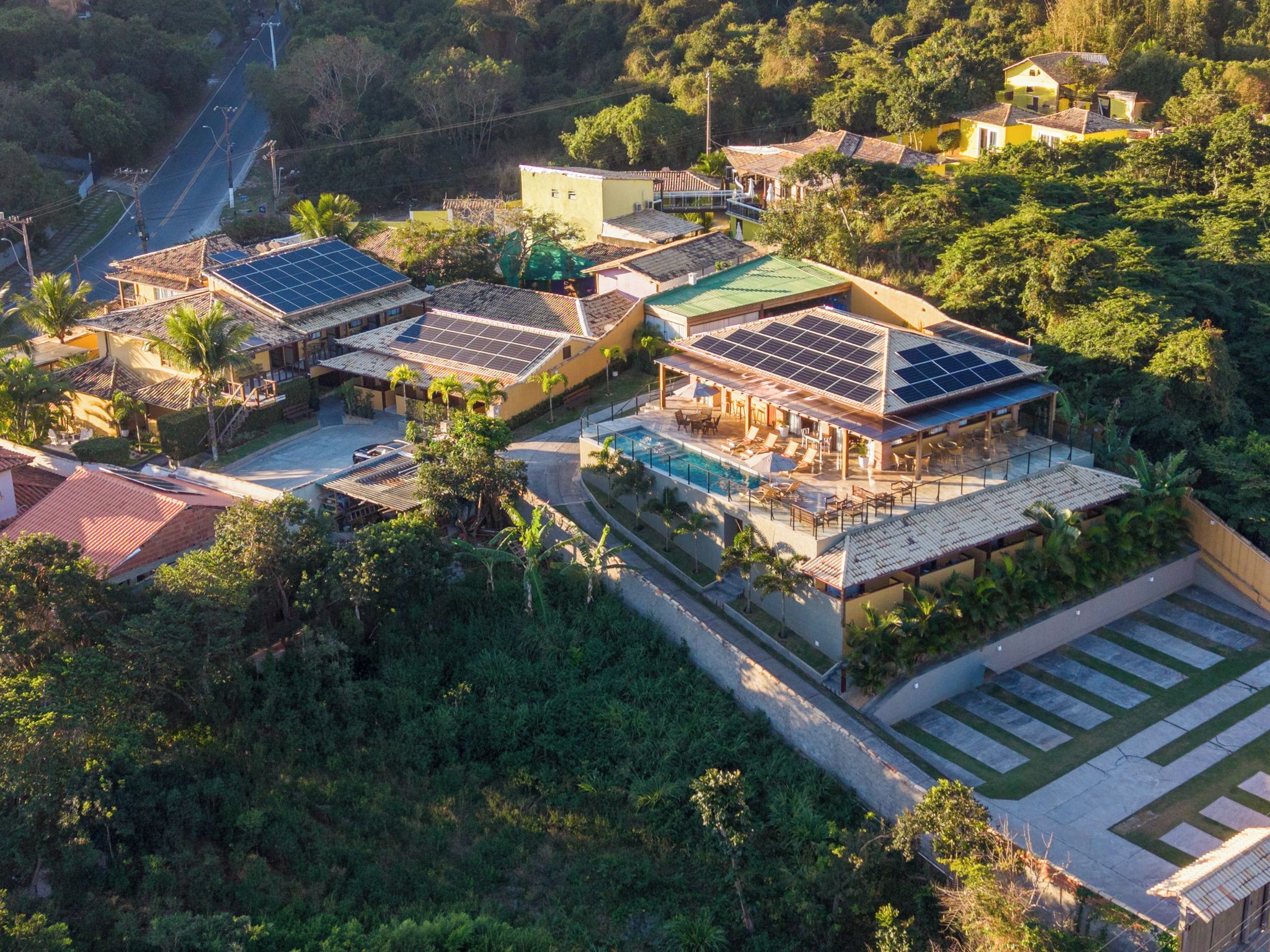 Una zona residencial con varios edificios, incluyendo una casa grande con piscina y paneles solares.