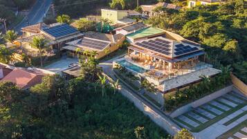 Una zona residencial con varios edificios, incluyendo una casa grande con piscina y paneles solares.