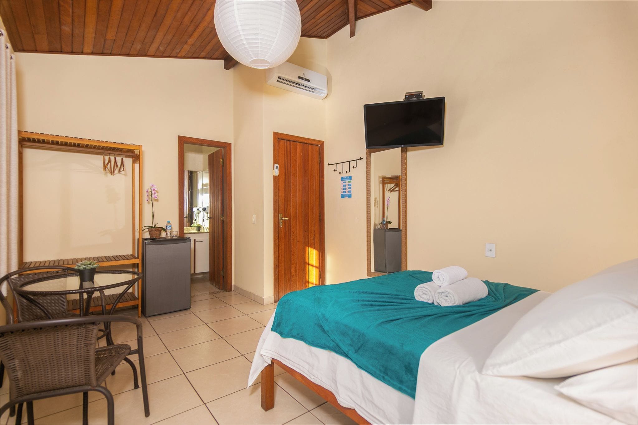 Een hotelkamer met een bed, een bureau, een stoel, een televisietoestel en een airconditioning.