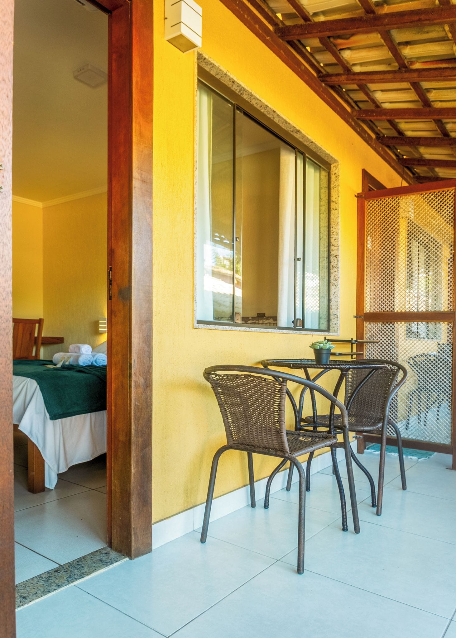 A room with a bed, a table with chairs, a window, and a door.