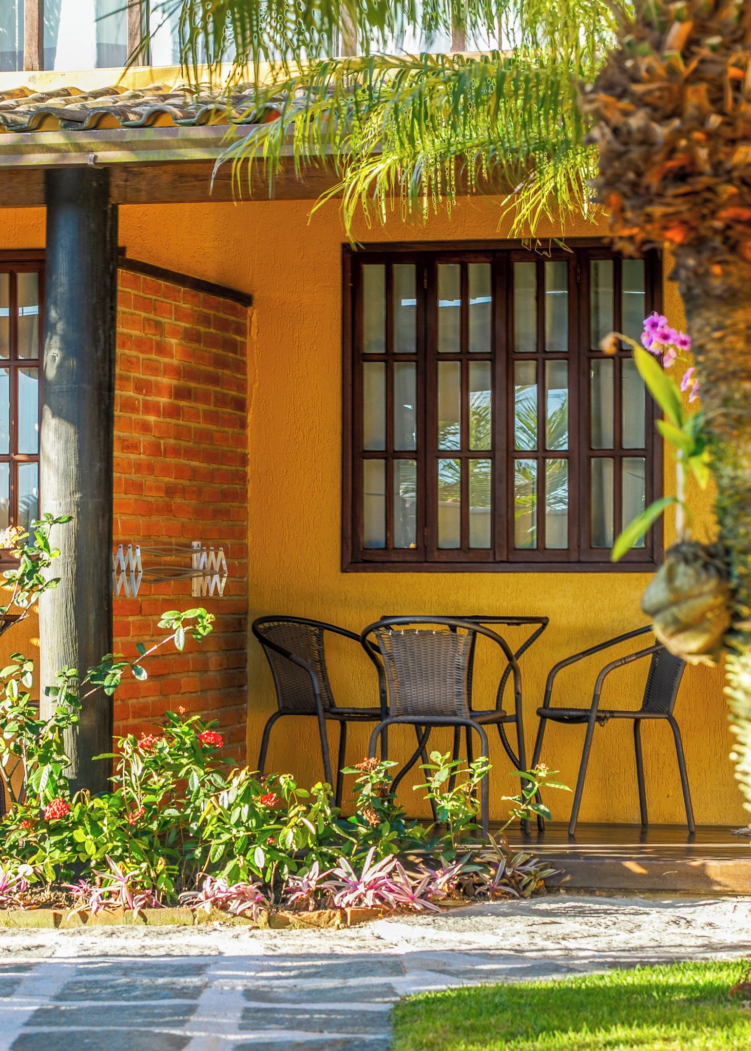 Un patio con mesa y sillas, un muro de ladrillo y una ventana con barrotes.