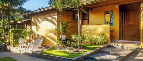 Una casa de dos pisos con un patio, mobiliario exterior y diversas plantas.