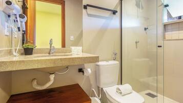 Un baño moderno con cabina de ducha de vidrio, inodoro y lavamanos con secador de pelo.
