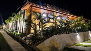 A modern hotel with a well-lit facade, a landscaped garden, and a concrete pathway. - Pousada Búzios Garden (Búzios)