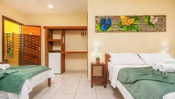 Habitación de hotel con dos camas, una mesita, una obra de arte colgada en la pared y una puerta con marco de madera.